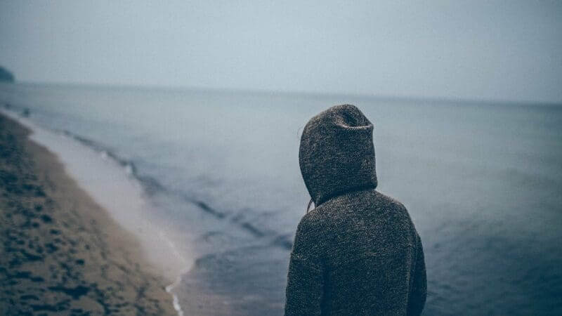person standing looking at the ocean and beach on a gloomy day